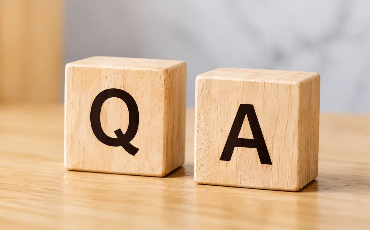 Two wooden blocks lettered Q and A on a light wooden desk — the ALLWINS packaging FAQs